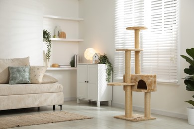 Photo of Stylish cat tree, chest of drawers and sofa in living room