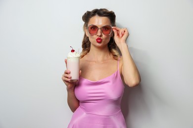 Photo of Beautiful woman with milk shake on light background. Pin-up vibe portrait