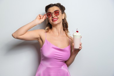 Photo of Happy woman with milk shake on light background. Pin-up vibe portrait