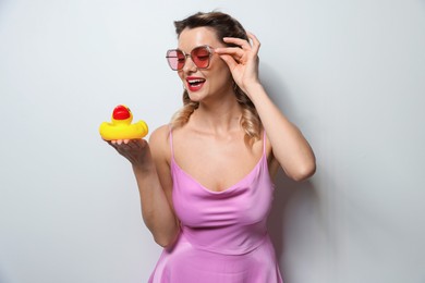 Photo of Happy woman with rubber duck on light background. Pin-up vibe portrait