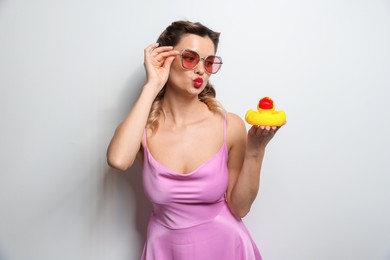 Photo of Beautiful woman with rubber duck on light background. Pin-up vibe portrait