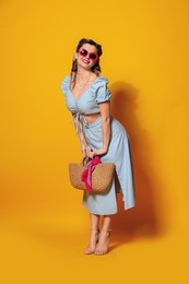 Photo of Happy pin-up woman in sunglasses posing with bag on orange background