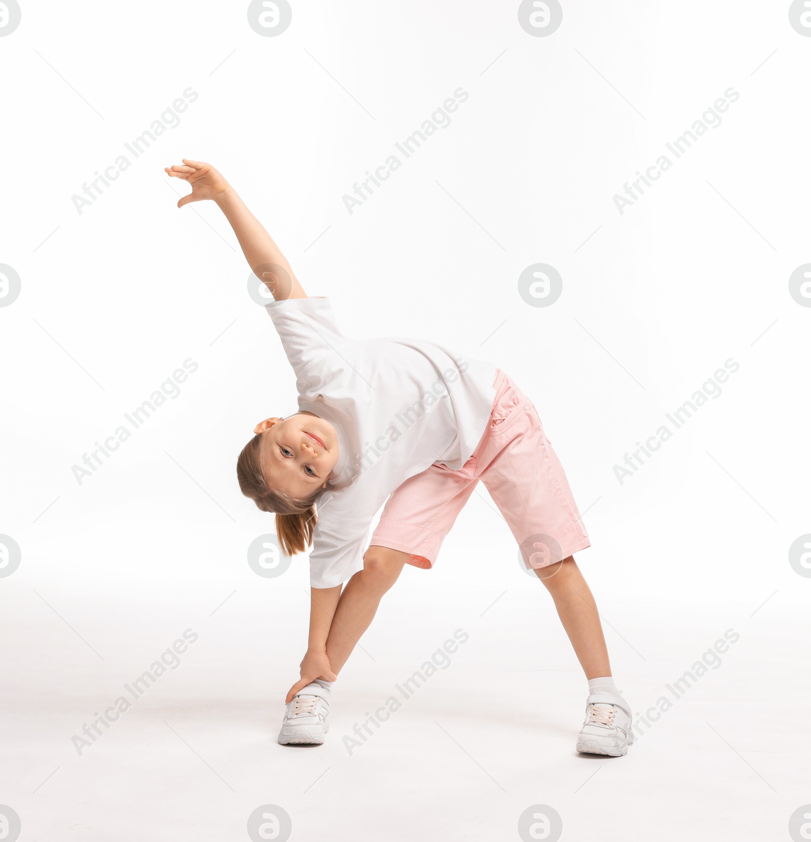 Photo of Cute little girl exercising on white background