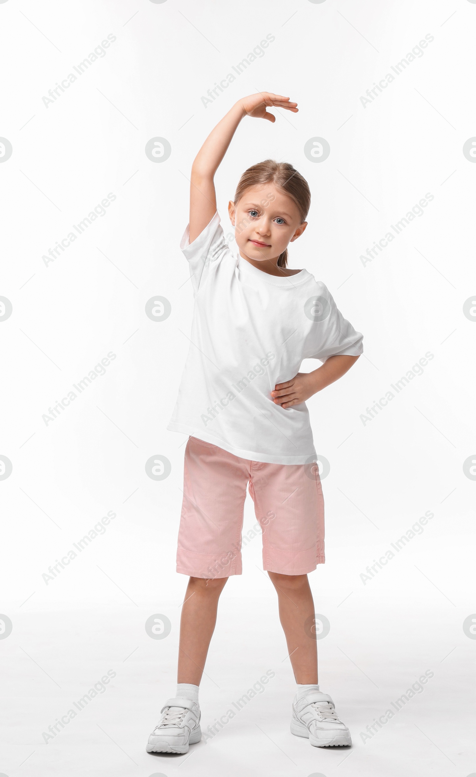 Photo of Cute little girl exercising on white background