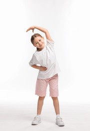 Photo of Cute little girl exercising on white background