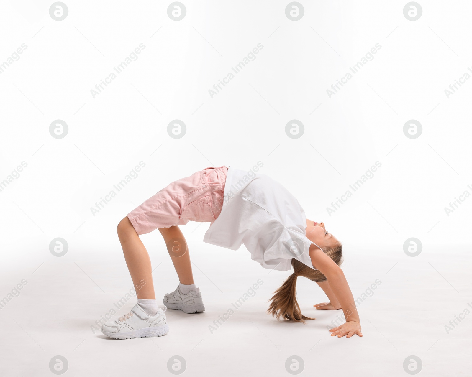 Photo of Cute little girl exercising on white background