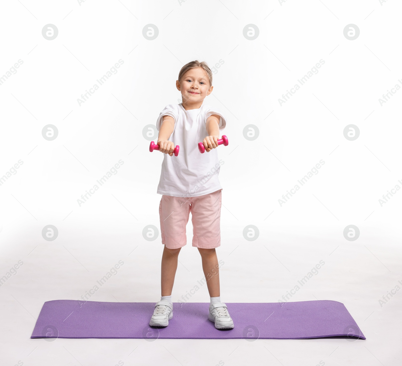 Photo of Little girl exercising with dumbbells on white background