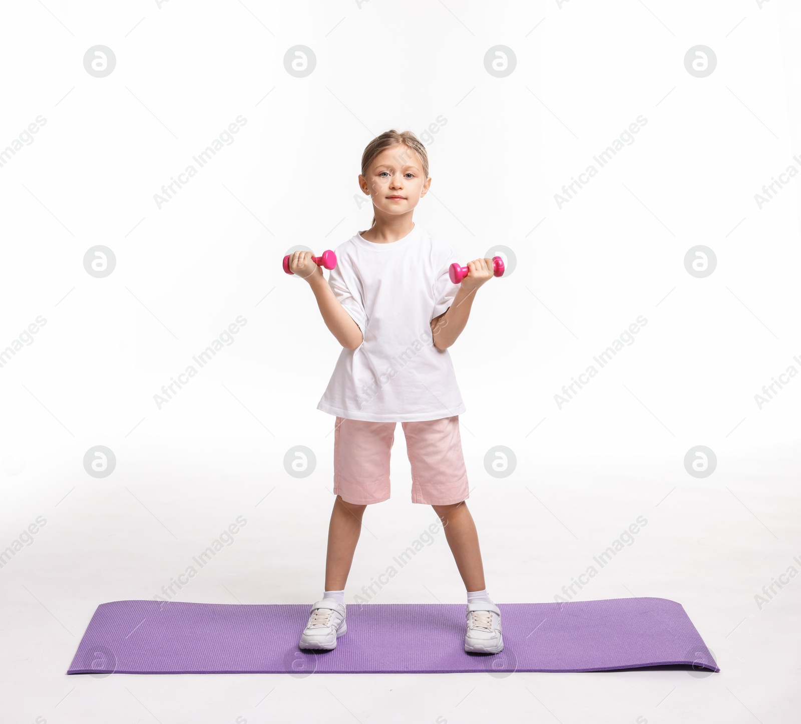 Photo of Little girl exercising with dumbbells on white background