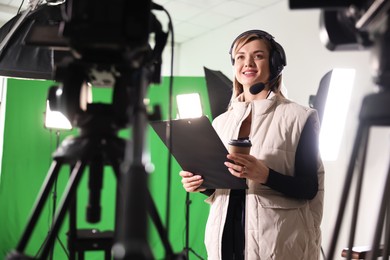 Photo of Happy young camerawoman with clipboard in modern film studio