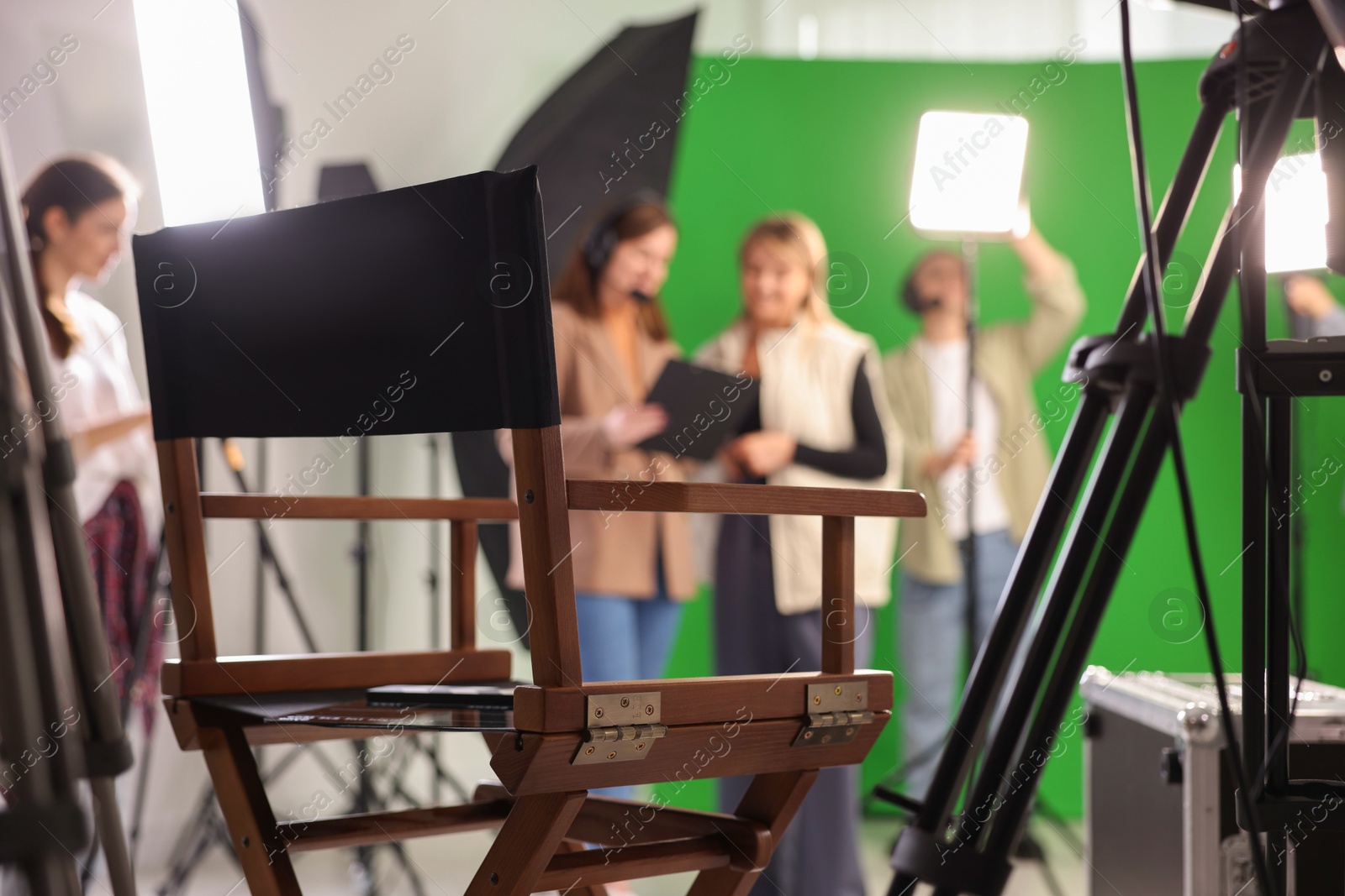 Photo of Group of people working in modern film studio, focus on chair