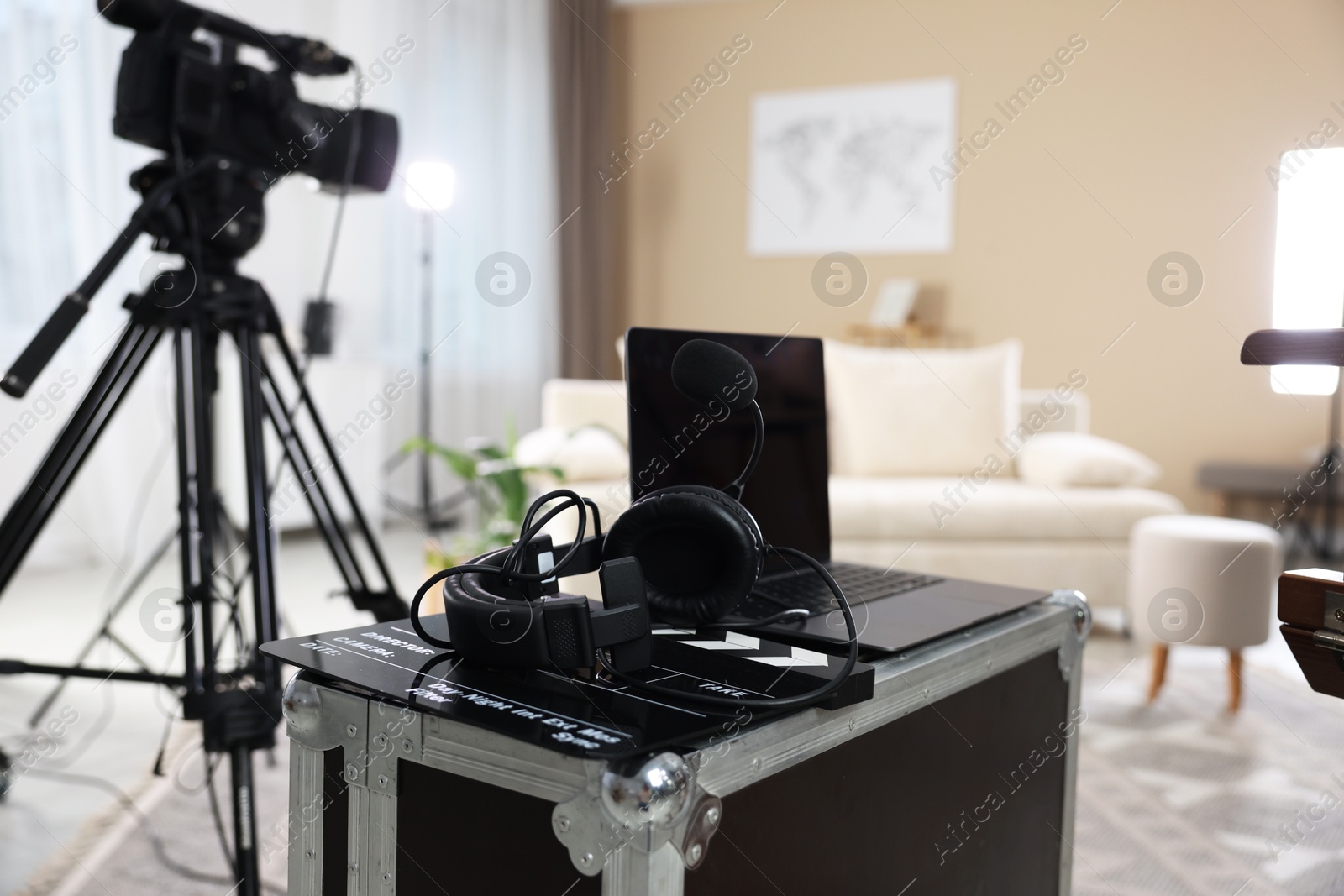 Photo of Headphones, camera, laptop and clapperboard in modern film studio, closeup