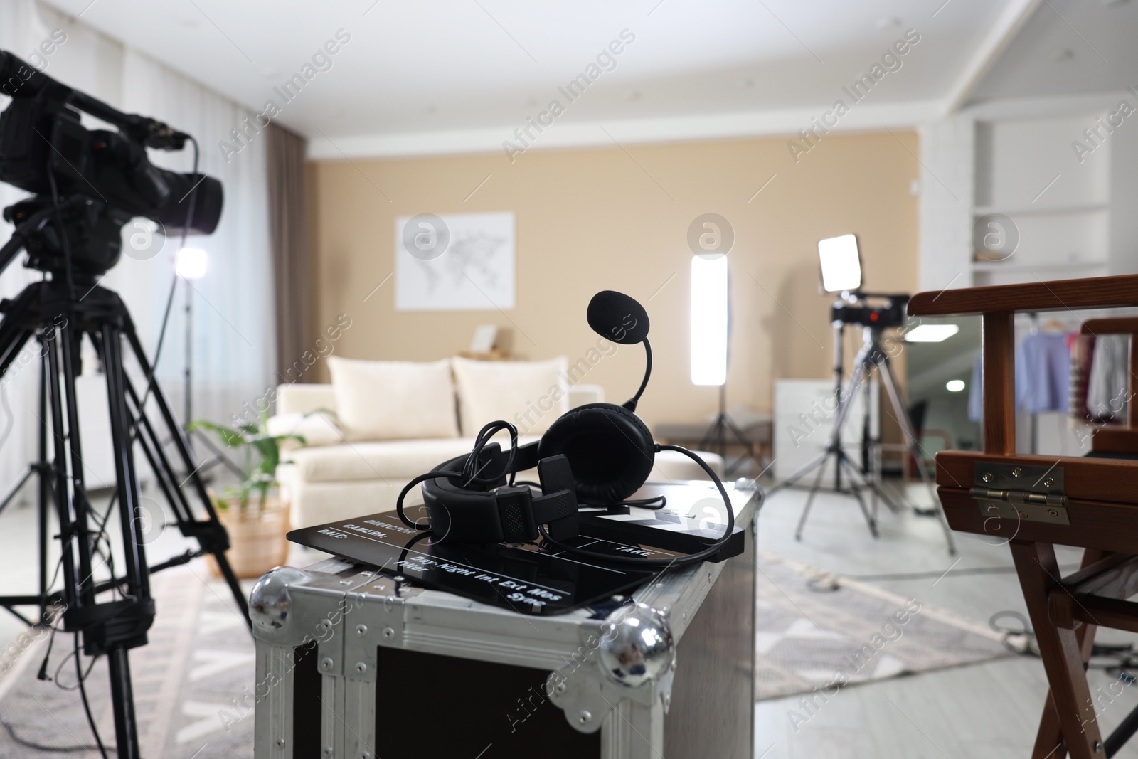 Photo of Headphones, camera, clapperboard and other professional equipment in modern film studio