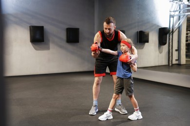 Photo of Girl in protective gloves having boxing practice with her coach at training center. Space for text