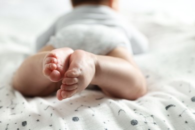 Photo of Little baby lying on bed indoors, closeup