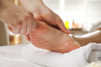 Photo of Woman receiving foot massage in spa salon, closeup