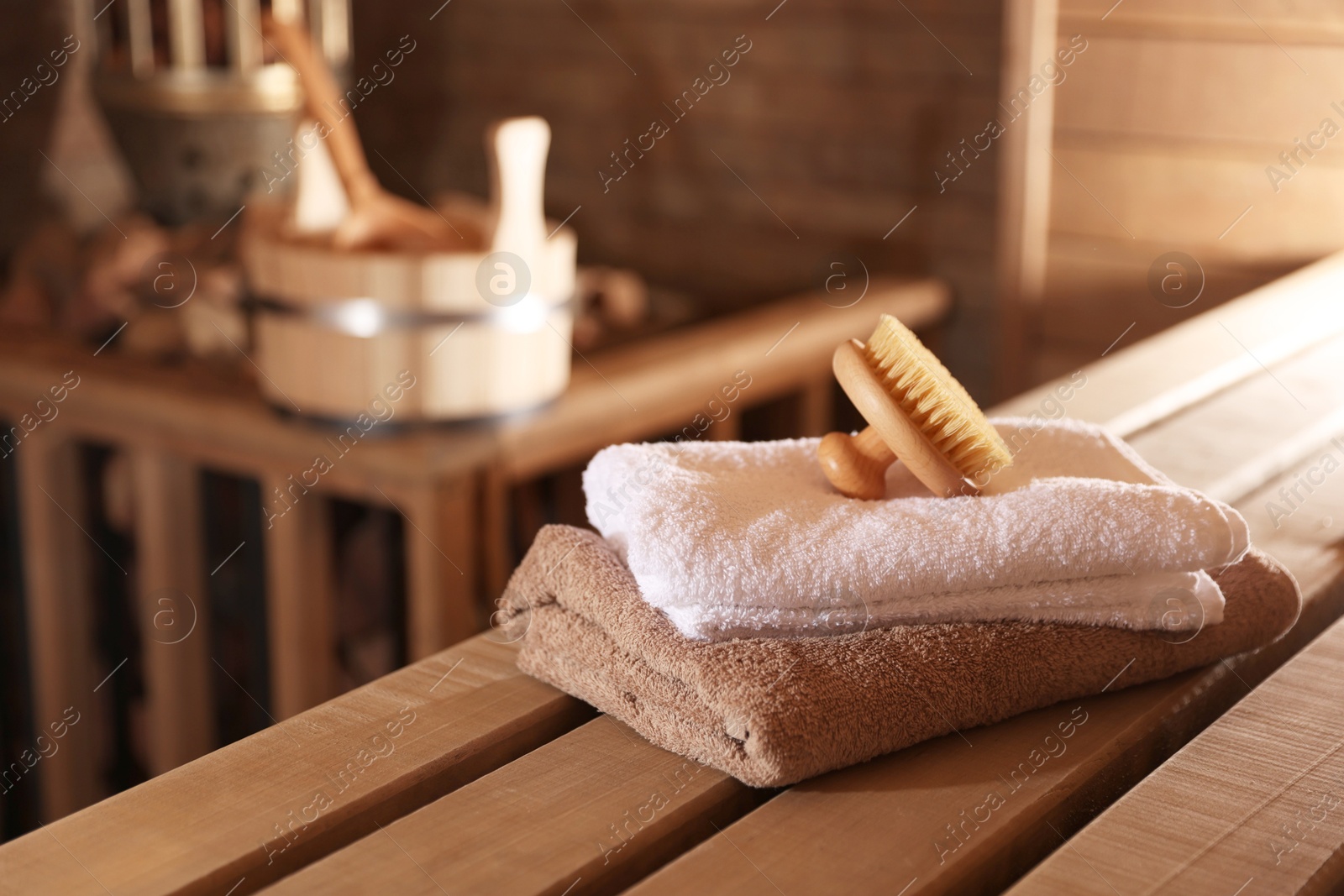 Massaging brush, stack of towels and other supplies in sauna Photo of Massaging brush, stack of towels and other supplies in sauna