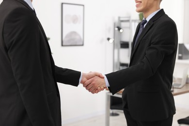 Photo of Businessmen shaking hands in agreement indoors, closeup