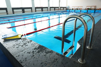 Photo of Swimming pool with clean water, ladder and lane dividers indoors