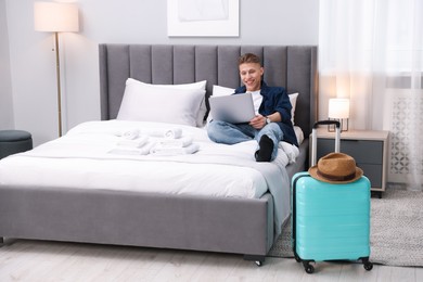 Photo of Man with laptop on bed in his hotel room