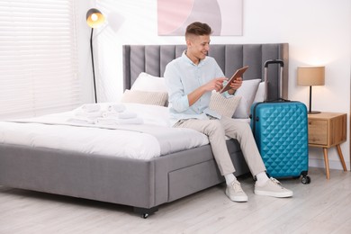 Photo of Man with tablet on bed in his hotel room