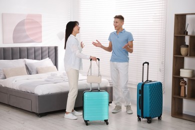 Photo of Happy couple with suitcases in hotel room