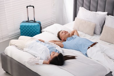 Photo of Happy couple lying on bed in their hotel room