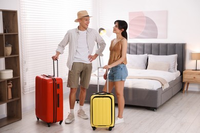 Photo of Happy couple with suitcases in hotel room