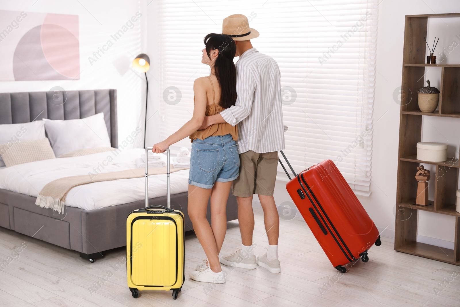 Photo of Happy couple with suitcases in hotel room