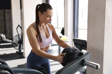 Photo of Athletic woman taking weight plate in gym