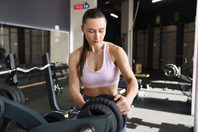 Photo of Athletic woman taking weight plate in gym