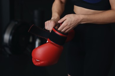 Photo of Woman wearing boxing glove on black background, closeup