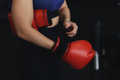 Photo of Woman with boxing gloves on black background, closeup