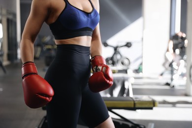 Photo of Woman wearing boxing gloves in gym, closeup. Space for text