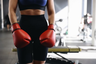 Photo of Woman wearing boxing gloves in gym, closeup. Space for text