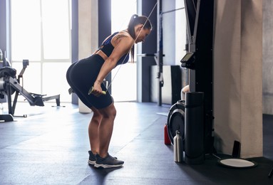 Photo of Athletic woman training with ski machine in gym