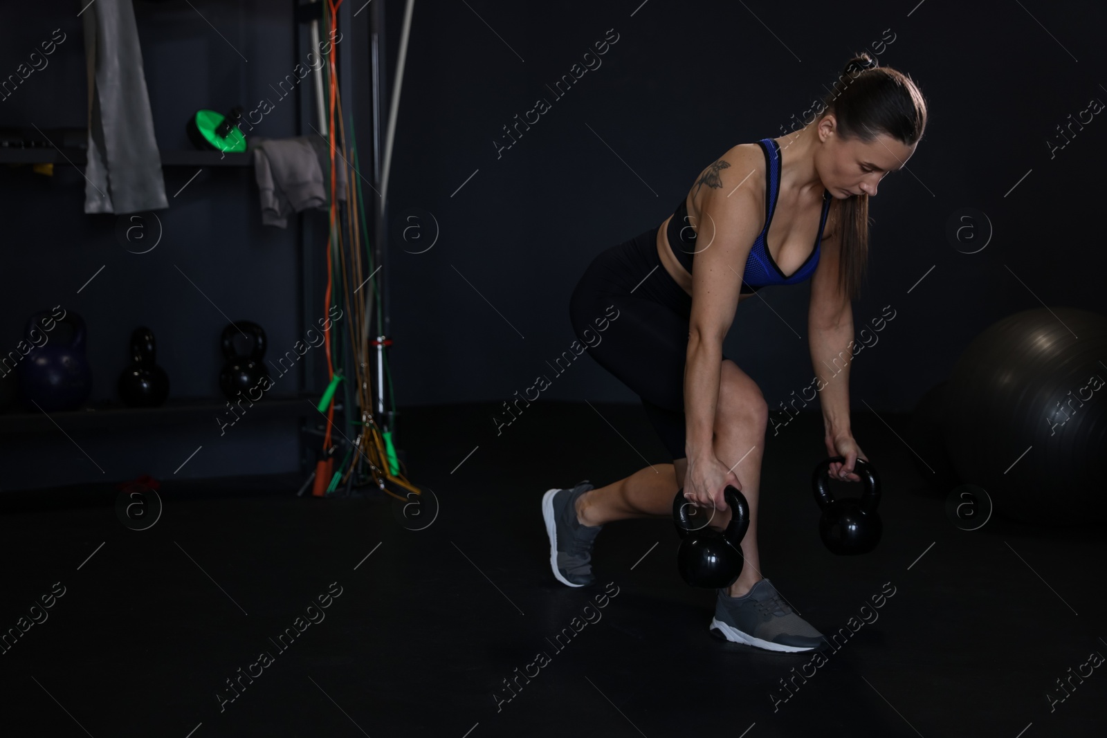 Photo of Athletic woman training with kettlebells in gym. Space for text