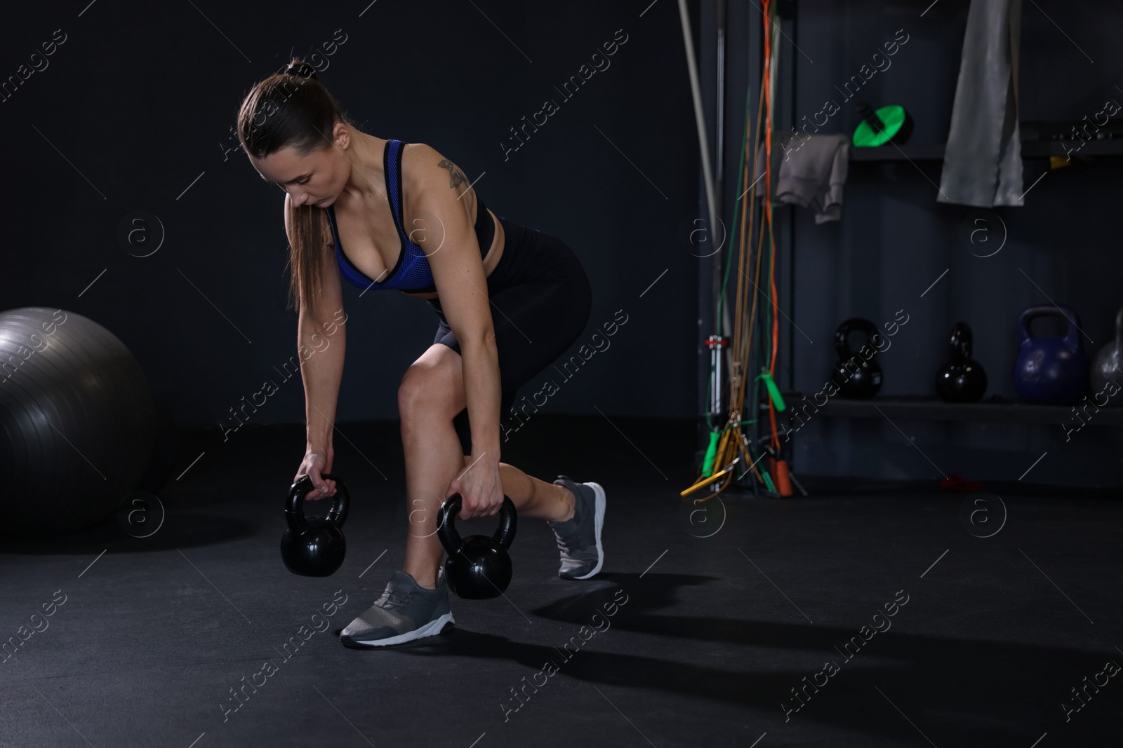 Photo of Athletic woman training with kettlebells in gym. Space for text