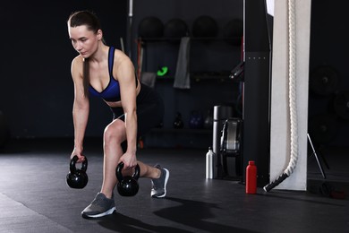 Photo of Athletic woman training with kettlebells in gym