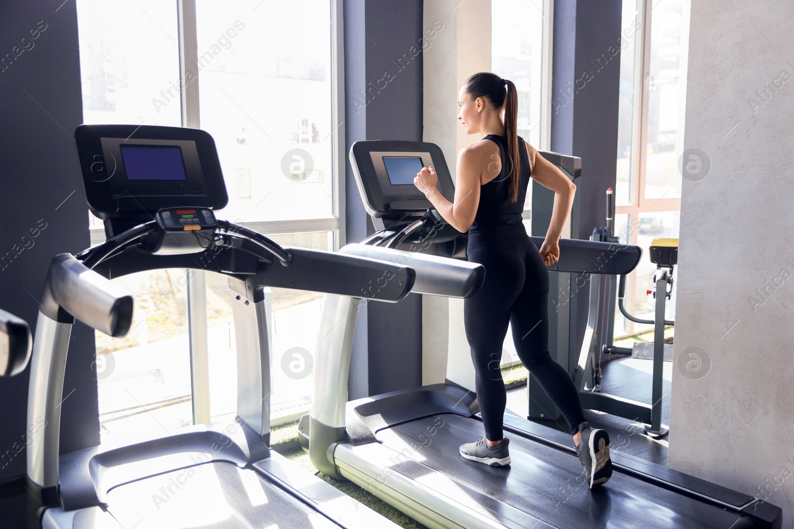 Photo of Athletic woman training on treadmill in gym