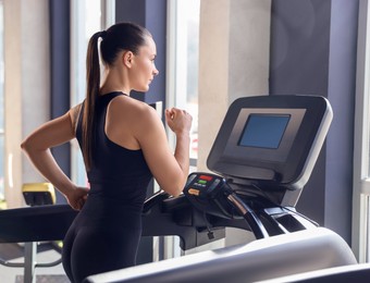 Photo of Athletic woman training on treadmill in gym