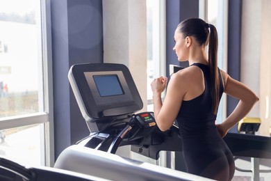 Photo of Athletic woman training on treadmill in gym