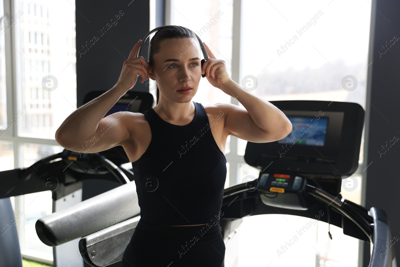 Photo of Athletic woman in headphones on treadmill in gym