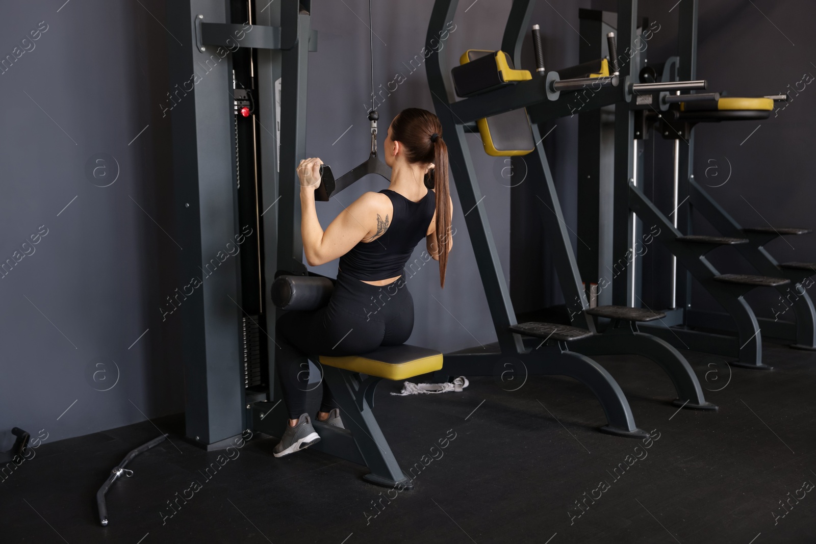 Photo of Athletic woman training on pulley machine in gym