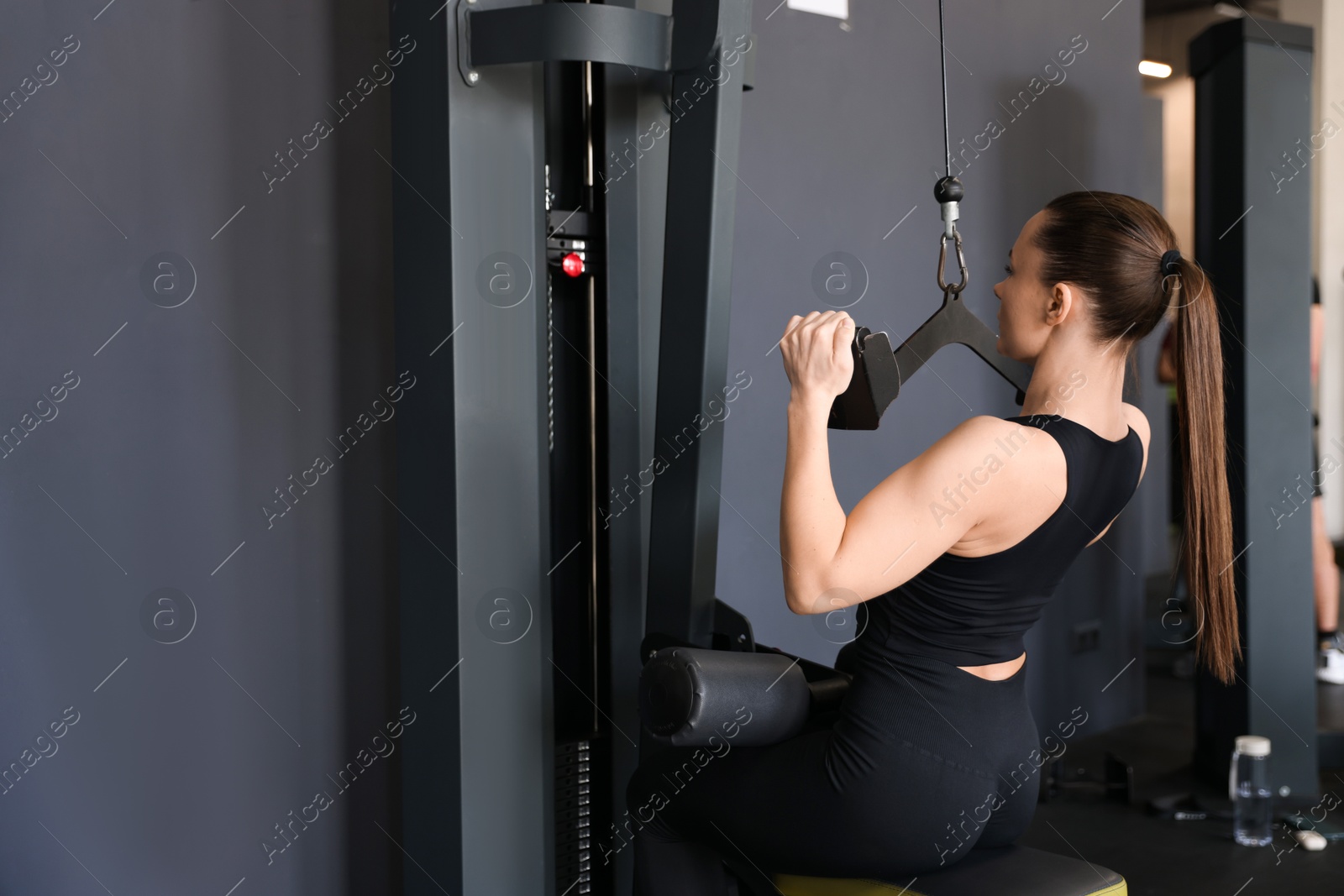 Photo of Athletic woman training on pulley machine in gym