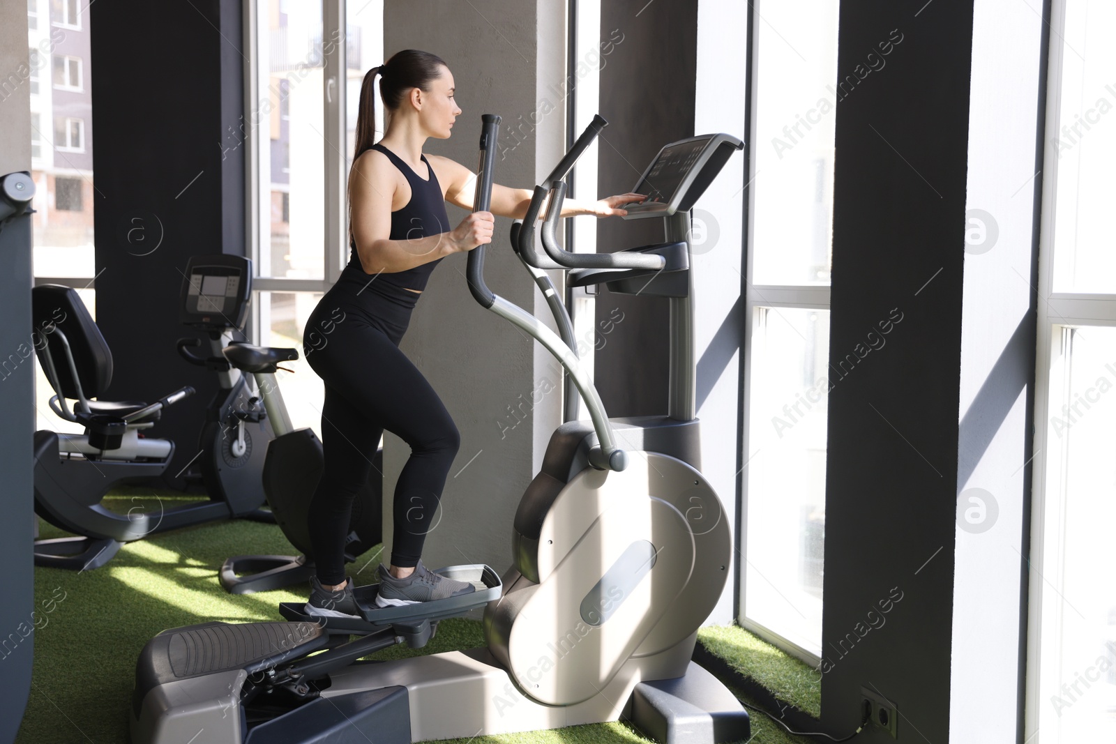 Photo of Athletic woman training on elliptical machine in gym