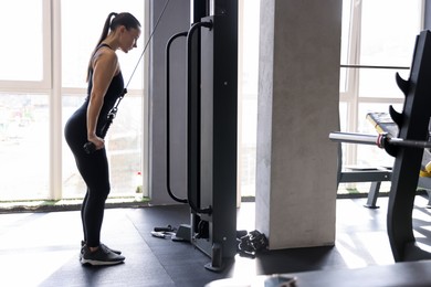 Photo of Athletic woman training on pulley machine in gym