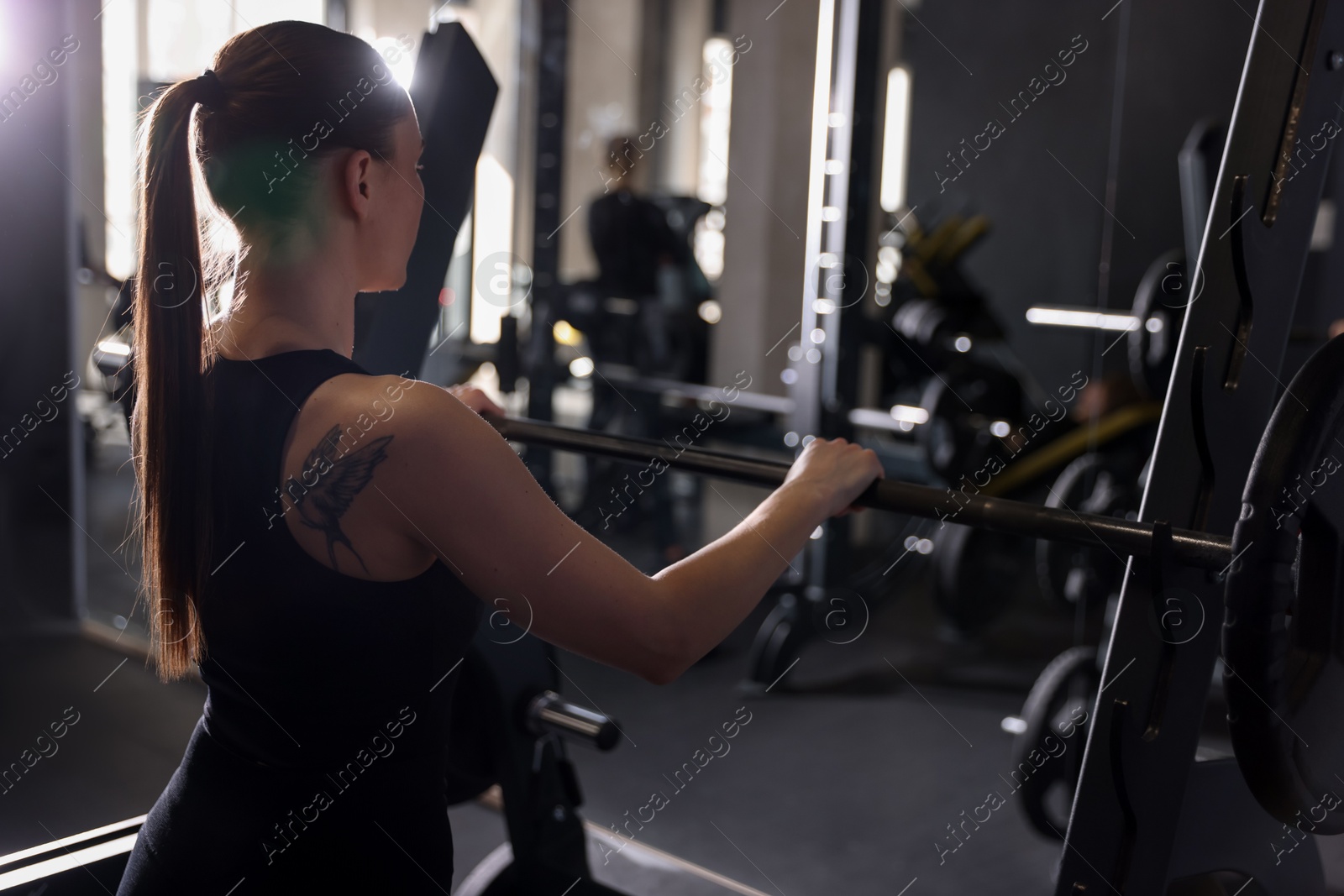 Photo of Athletic woman training with barbell in gym