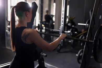 Photo of Athletic woman training with barbell in gym