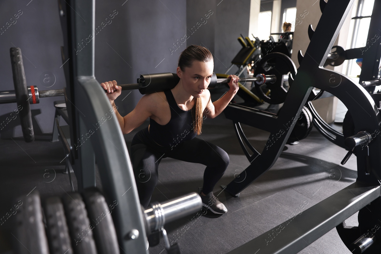 Photo of Athletic woman training with barbell in gym