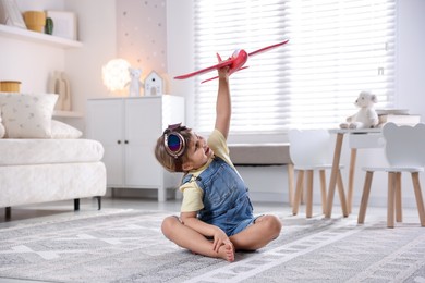 Photo of Cute little girl playing with toy plane at home